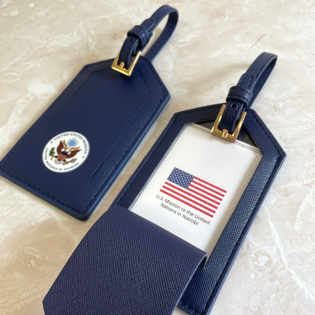 Etiqueta maleta personalizada en cuero azul marino con logo institucional — acabado premium