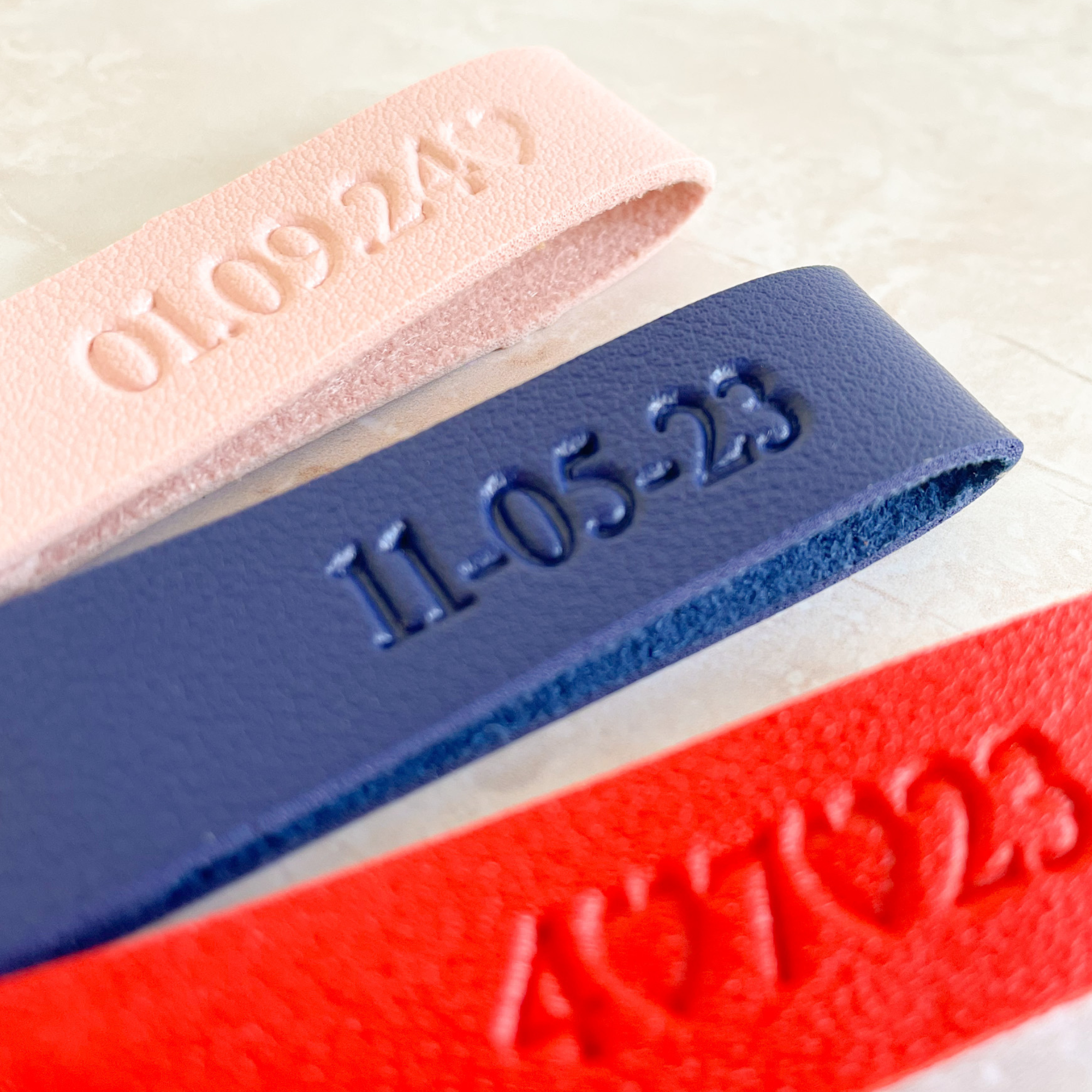 Detalle de llaveros de cuero personalizados con fecha en relieve en azul marino y rojo